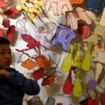 A child in front of drawings of objects.